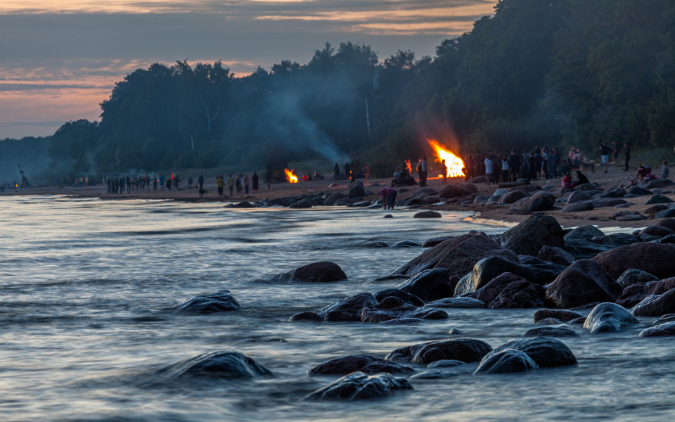 Menschen feiern die Johannisnacht mit gro&szlig;en Lagerfeuern am Sandstrand der Ostsee