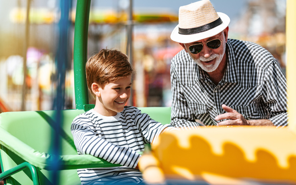 Ein Gro&szlig;vater und sein Enkel auf einem Fahrgesch&auml;ft im Legoland Deutschland, beide l&auml;cheln und genie&szlig;en die Zeit zusammen.